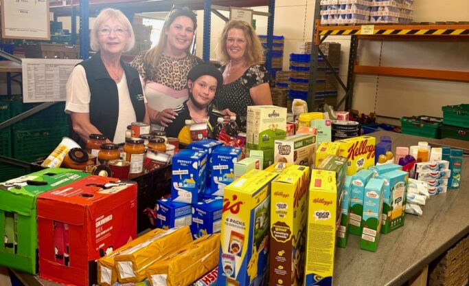 Three food donors and food bank coordinator, Dorothy tanding behind a table full of food donations.