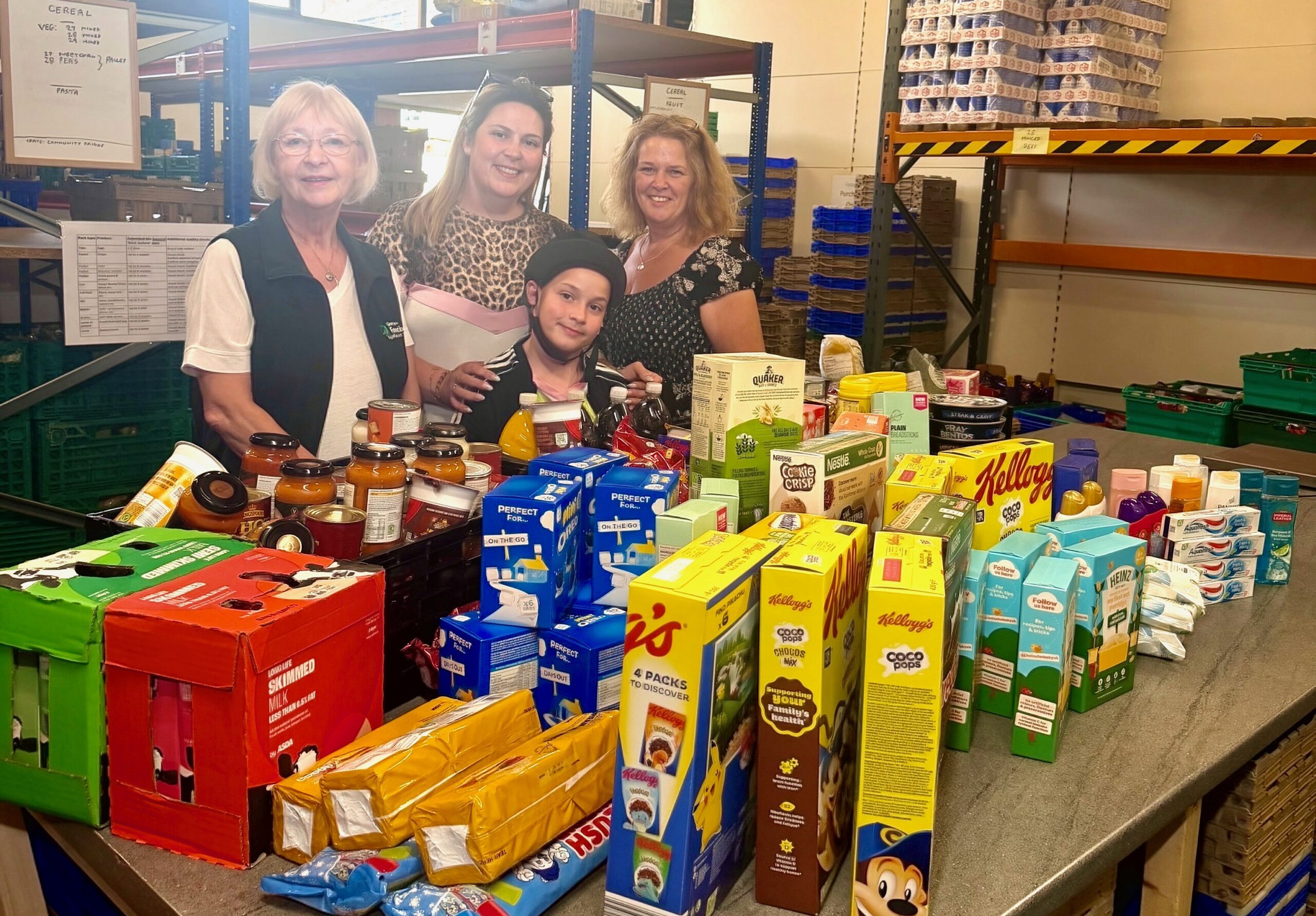 Three food donors and food bank coordinator, Dorothy tanding behind a table full of food donations.