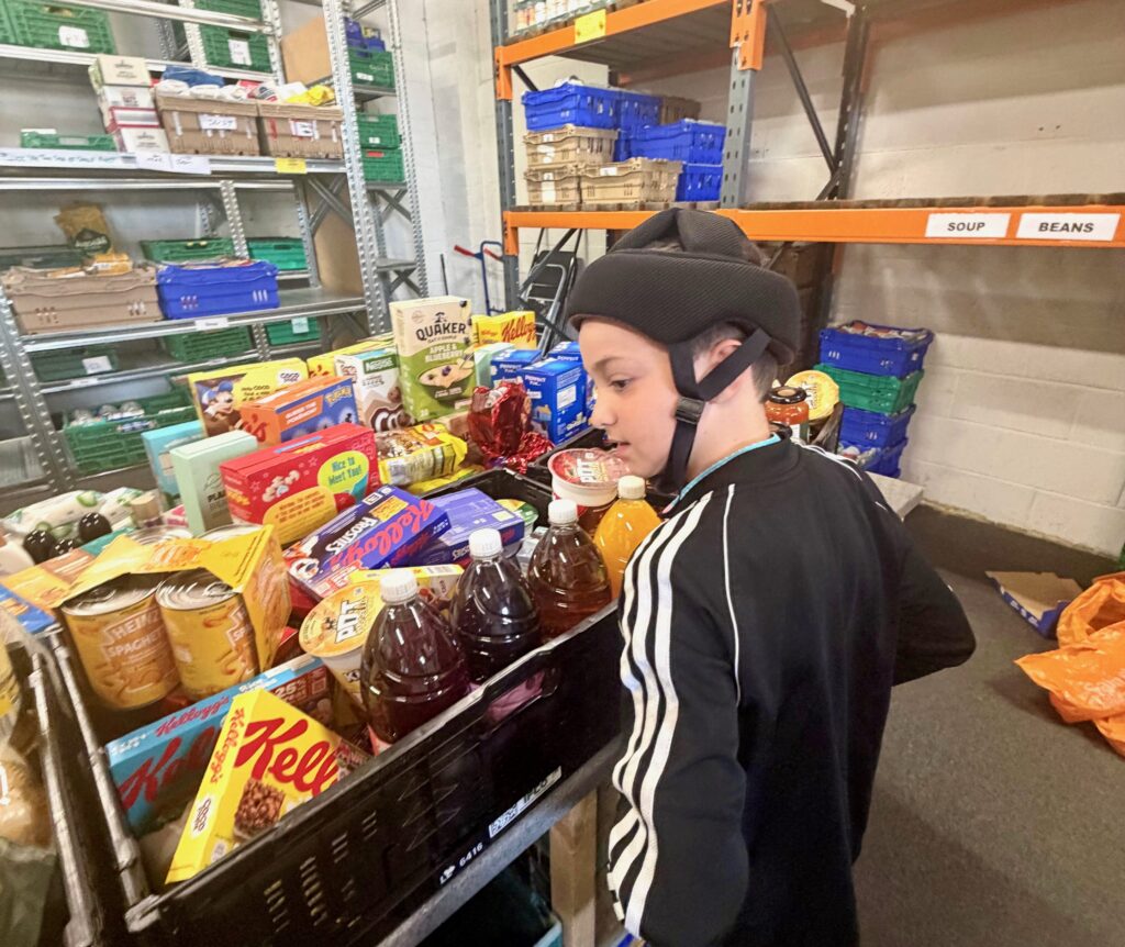 Young boy Harry stood beside his donation of cereals, juices, pasta, rice and ice pops
